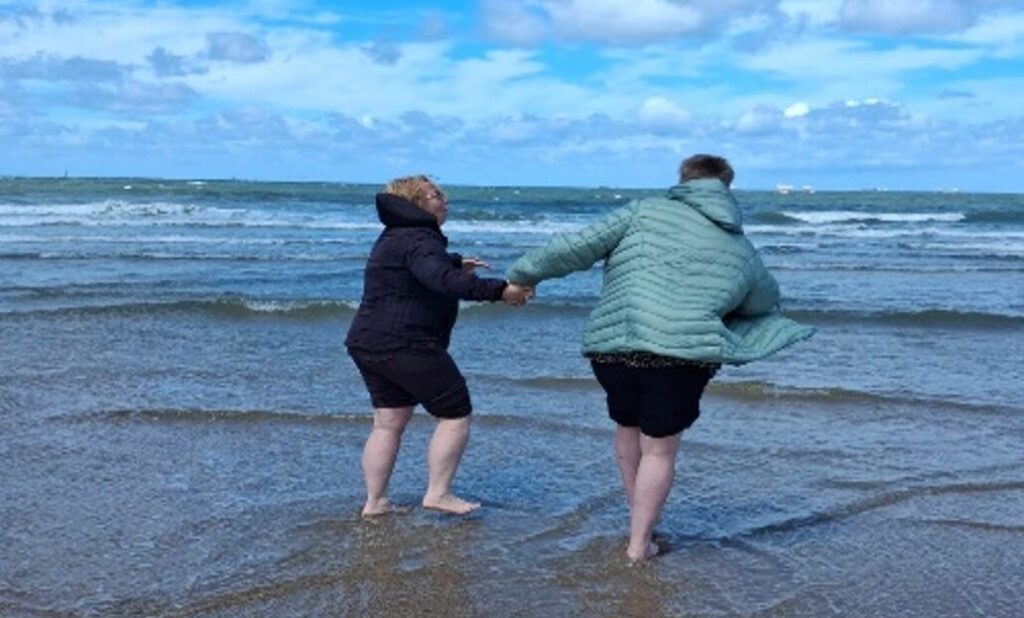 Bianca en haar vriendin samen met hun voeten in de zee bij Scheveningen.